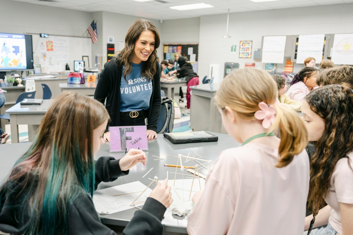 Taylor Rice, SRNS Education Outreach Programs Lead, collaborates with students as they reinforce their models, ensuring their structures can withstand the simulated earthquakes.