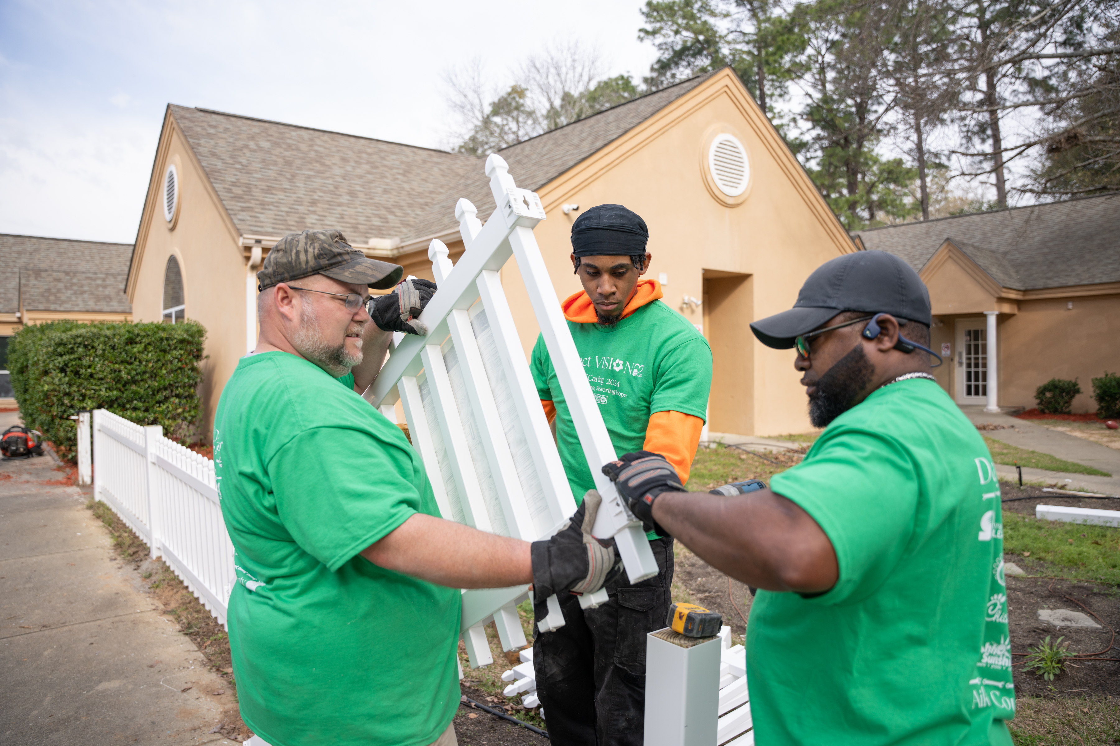 Project Vision volunteers work on a fence as part of a community service project.